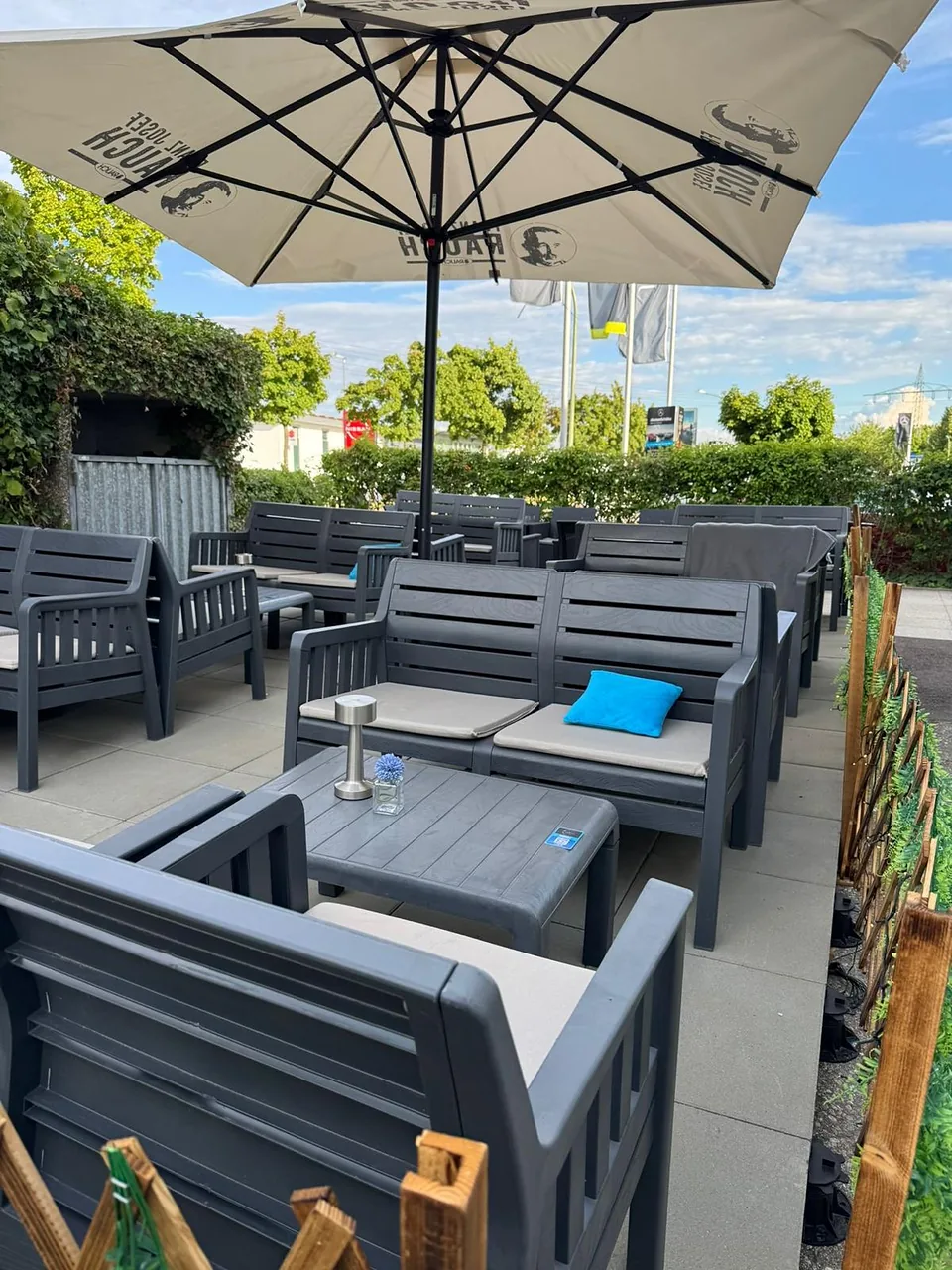 Lounge-Sofas mit blauen Kissen unter dem Sonnenschirm auf der Terrasse